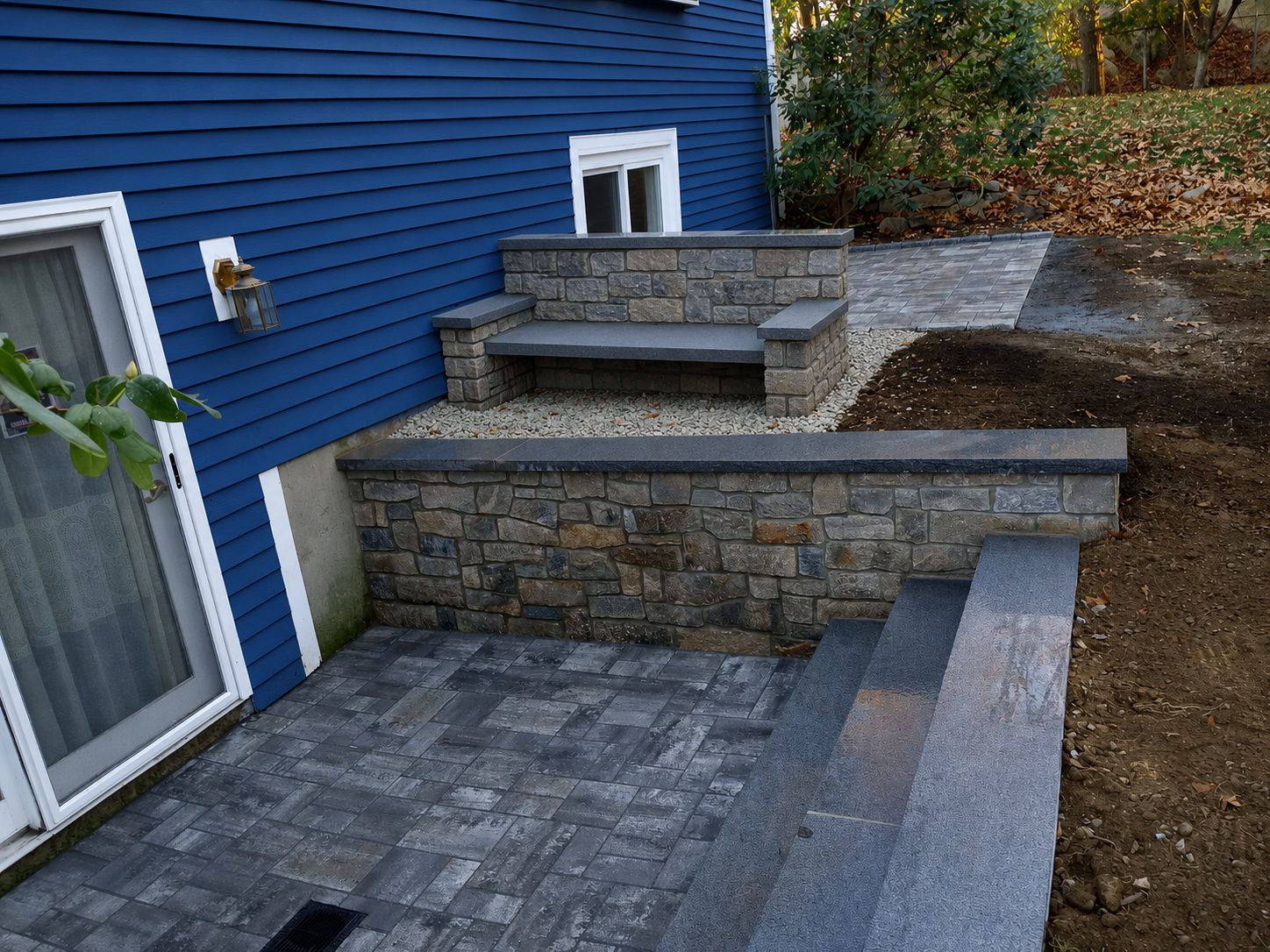 Multi-level paver patio with stone seating wall and bluestone caps