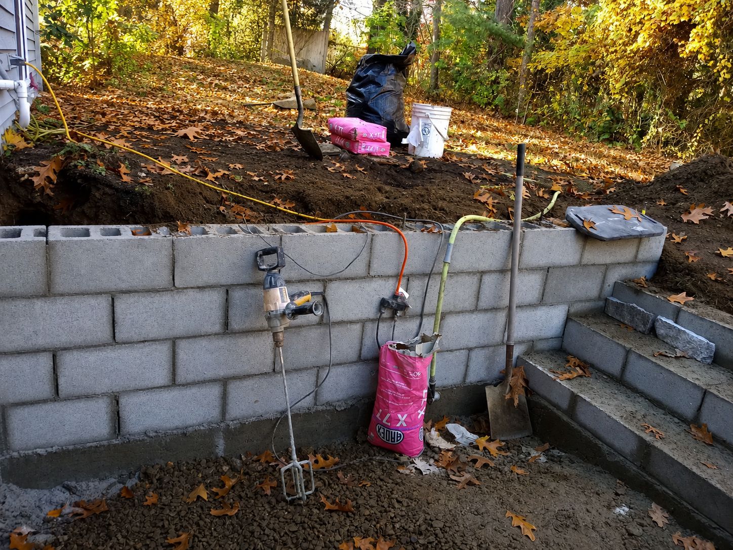 Concrete block retaining wall under construction with proper drainage
